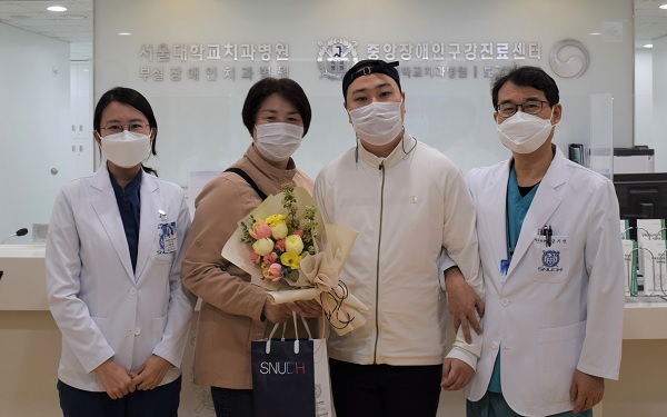 20일 첫 내원환자에게 꽃다발과 기념품을 전달했다. 중앙장애인구강진료센터 곽은정 교수(왼쪽)와 금기연 부설 장애인치과병원장(오른쪽).